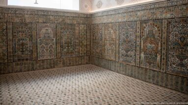 Corner of a tiled Bardo Museum room with tall polychrome panels of architectural niches, flowers, borders, and a patterned tile floor.
