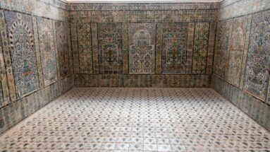 Symmetrical tiled chamber with multicolored wall panels, stylized niches, floral decoration, and a patterned ceramic floor.