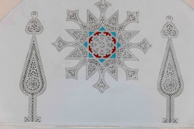 Pale wall decoration with a central multicolored star medallion flanked by two tall teardrop-shaped arabesque motifs.