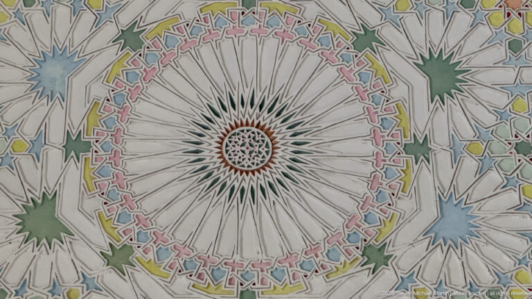 Large radial ceiling rosette with narrow white segments, a multicolored geometric border, and surrounding green and blue star motifs.
