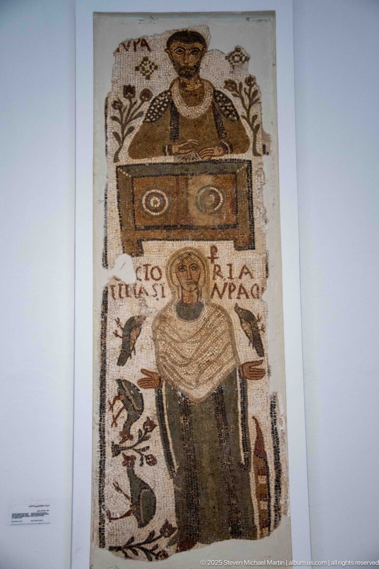 Tall Christian mosaic with two frontal figures in separate registers, Latin text, birds, and vegetal motifs.