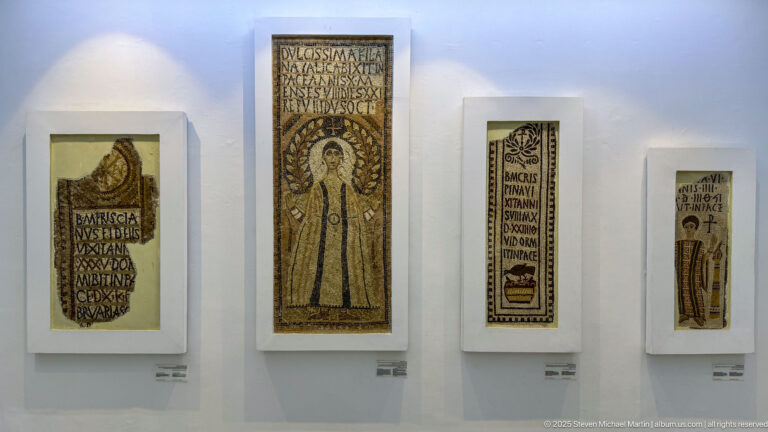 Four tall Christian funerary mosaics displayed together, with portraits, Latin inscriptions, vessels, crosses, and floral motifs.