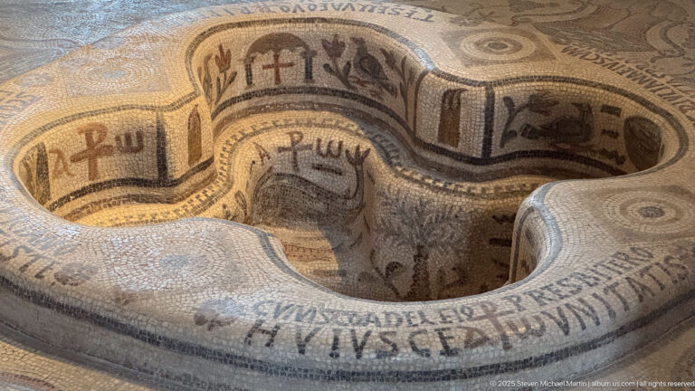 Interior of the four-lobed Demna baptismal font with mosaic inscriptions and Christian symbols covering its curved basin walls.