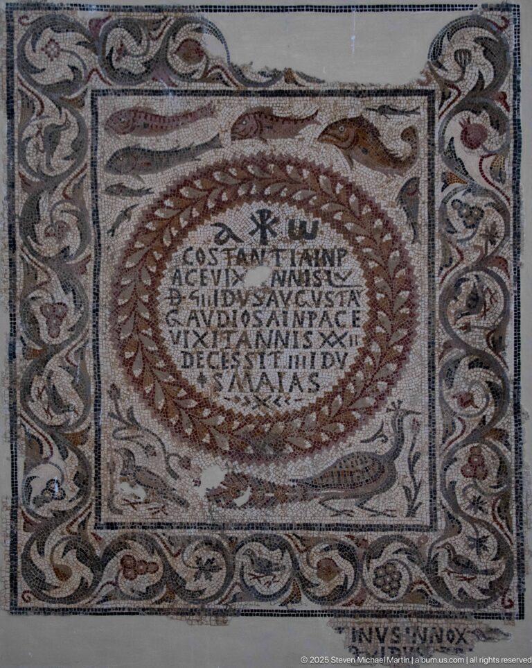 Christian mosaic with multi-line Latin inscription inside a wreath and broad scrolling vegetal border.