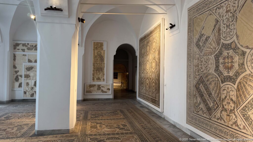 Arched Bardo Museum gallery with geometric floor mosaics and large figural and decorative wall panels.
