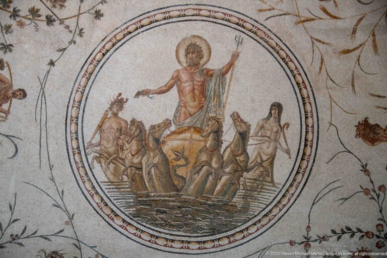 Neptune holding a trident on a marine chariot with a Triton and Nereid in the central medallion of a Roman mosaic.