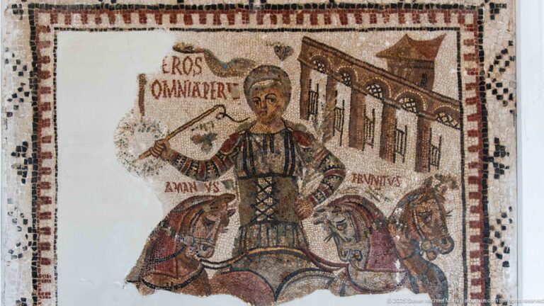 Mounted male figure with horses and a building in an inscribed Roman mosaic reading EROS OMNIPOTENS.