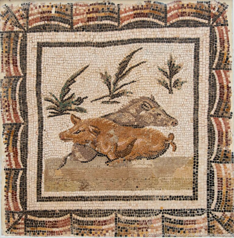 Two small brown game animals lying beneath sparse plant motifs in a framed Roman mosaic panel.
