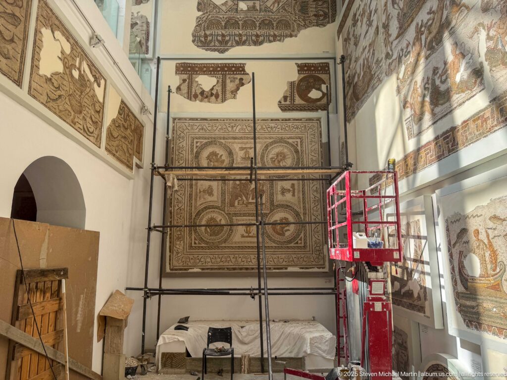 Bardo Museum gallery with scaffolding and red lift equipment positioned beside monumental wall-mounted mosaics.