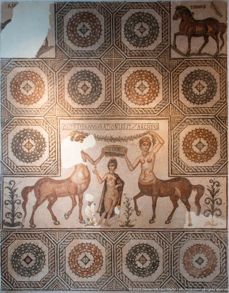 Venus standing between two centauresses who hold a victory crown above her head in a fourth-century Roman mosaic.