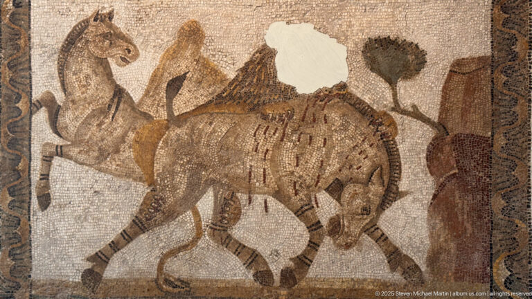 Large spotted or striped wild feline-like animal walking beneath trees and birds in a Roman mosaic.