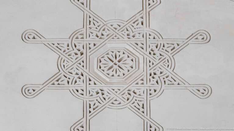 Pale carved plaster panel with an eight-pointed interlaced star motif centered on a small rosette.
