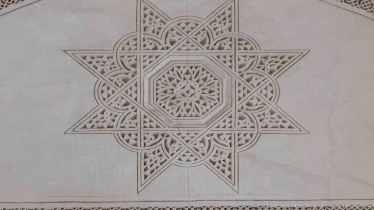 Large pale plaster medallion with interlaced eight-pointed star, central rosette, and fine carved geometric details.