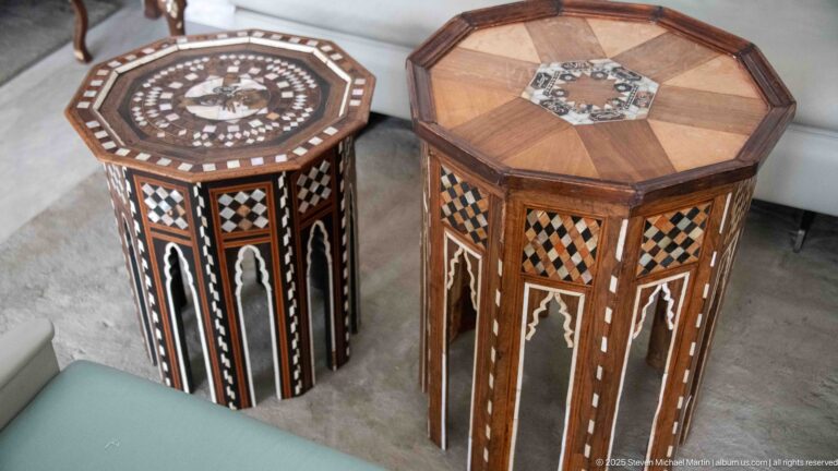 Two tall octagonal wooden side tables with different geometric inlay patterns and contrasting dark-and-light panel decoration.
