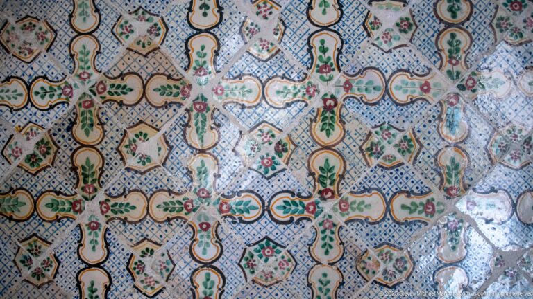 Close view of dense blue, cream, green, and red ceramic tilework arranged in repeating geometric and floral motifs.