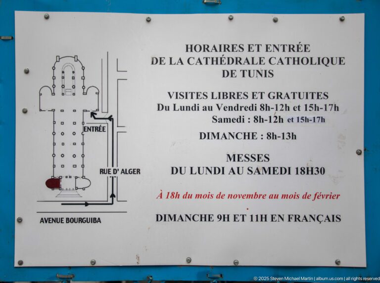French cathedral information sign with floor plan, entrance location, visiting hours, and Mass schedule beside Avenue Bourguiba and Rue d’Alger.