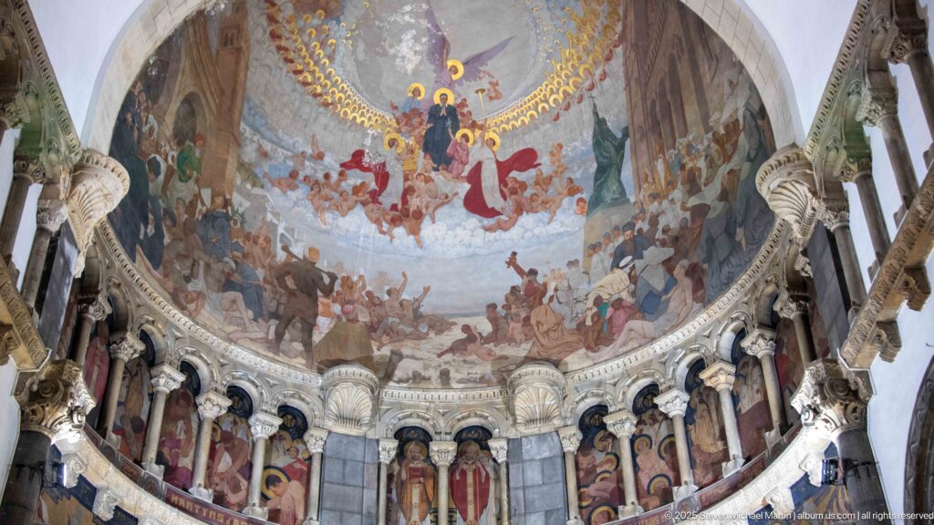 Large apse mural with a radiant central religious scene above painted standing saints set between carved columns.