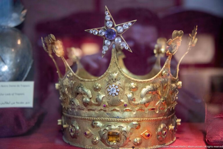 Gilded ceremonial crown set with colored stones and floral ornaments, with tall points and a star-shaped finial.