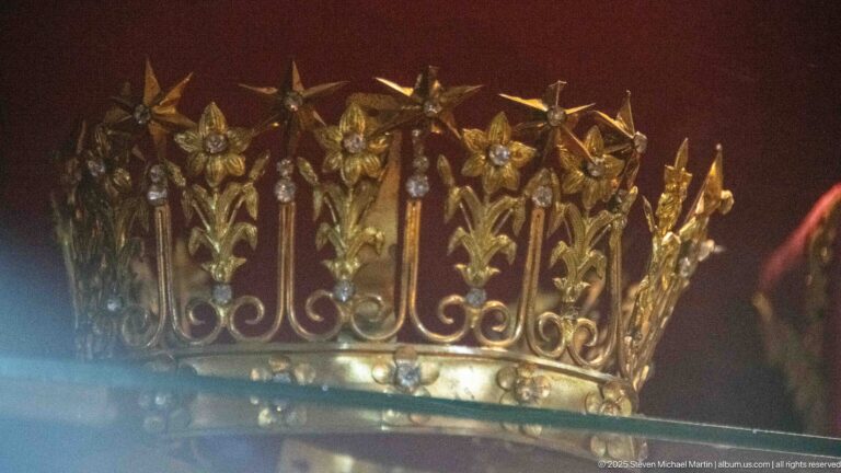 Openwork gilded crown formed from lily-like flowers, curling stems, leaves, and small jewel-like floral centers.