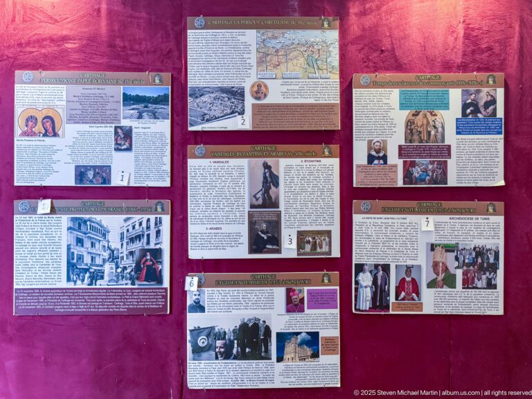 Wide wall exhibition with French historical panels, maps, portraits, archival photographs, and documentary images on burgundy fabric.