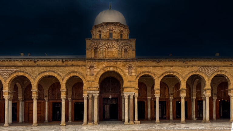 Stone arcade and domed central bay of the Zitouna Grand Mosque seen across the open courtyard.