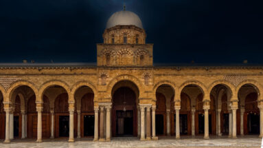 Stone arcade and domed central bay of the Zitouna Grand Mosque seen across the open courtyard.