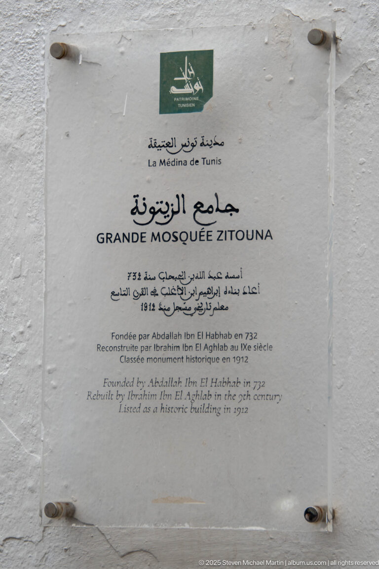 Multilingual wall plaque reading Grande Mosquée Zitouna with Arabic, French, and English historical text.