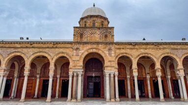 Symmetrical Zitouna Grand Mosque courtyard façade with domed central entrance and rows of horseshoe arches.