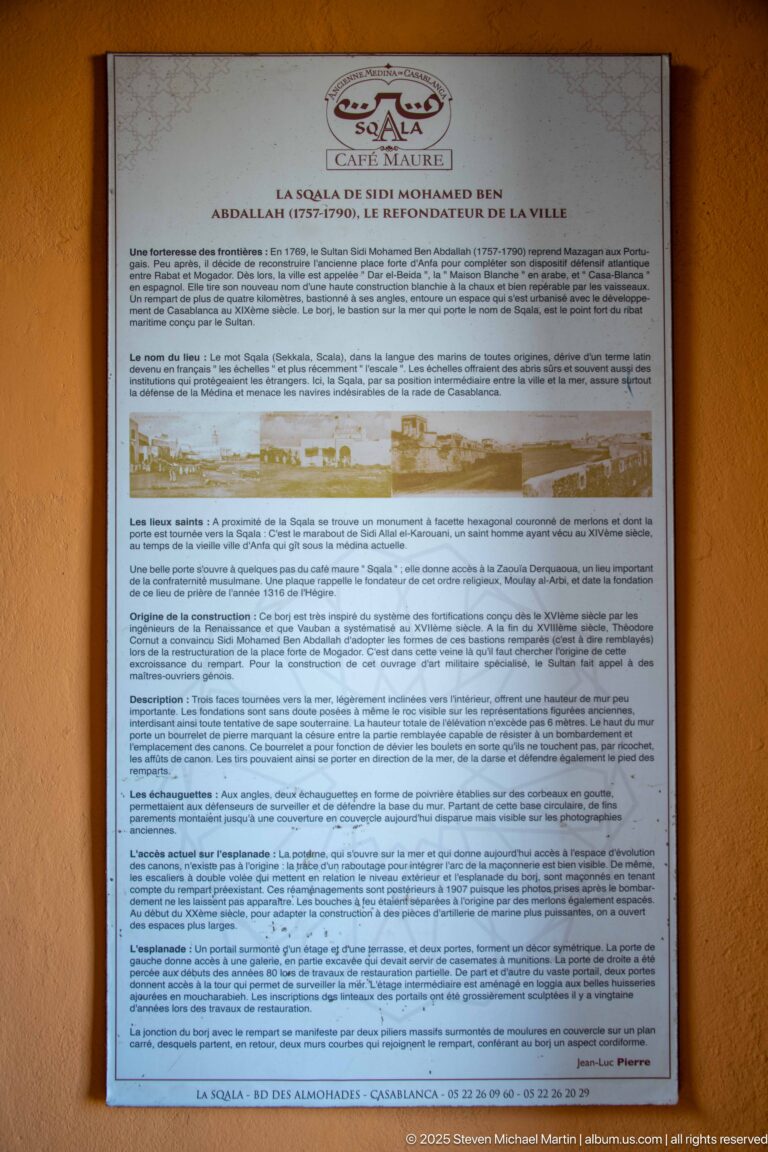 French-language information panel mounted on an ochre wall, with a small site plan and dense explanatory text.