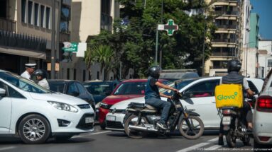 Motorcyclists and cars crowd a Casablanca street, including a courier with a yellow Glovo delivery box.