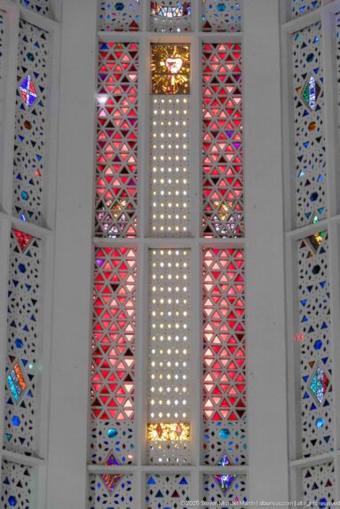 Close view of red triangular stained-glass lattice flanking a pale perforated central panel with small colored accents.