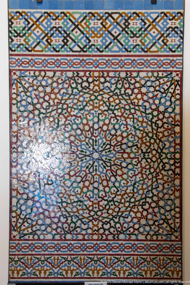 Rectangular multicolored zellij panel with dense radial geometry and patterned border bands.