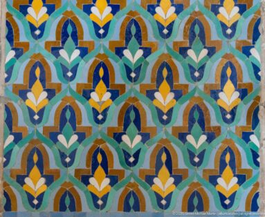 Repeating stylized floral mosaic in turquoise, blue, green, white, ochre, and yellow.