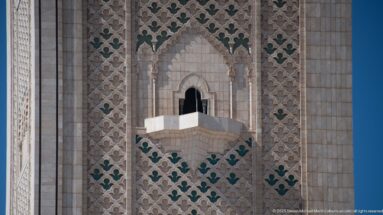 Small dark arched opening with projecting stone ledge set in the patterned minaret façade.
