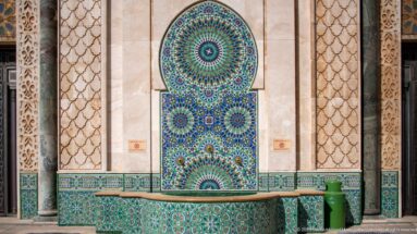 Stone basin beneath a tall blue-green mosaic niche with geometric rosettes.