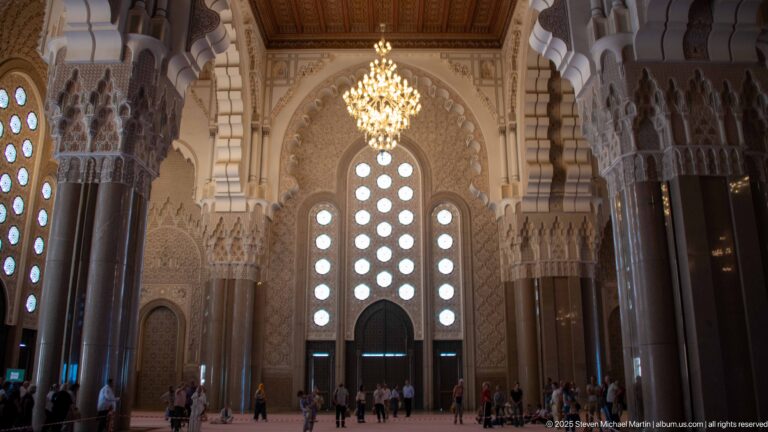Large mosque doorway beneath circular windows, framed by dark columns and carved capitals.
