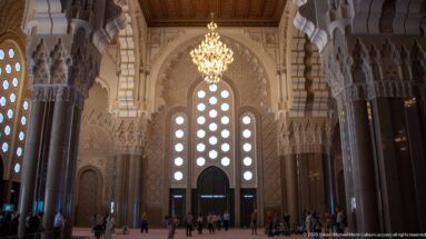 Large mosque doorway beneath circular windows, framed by dark columns and carved capitals.