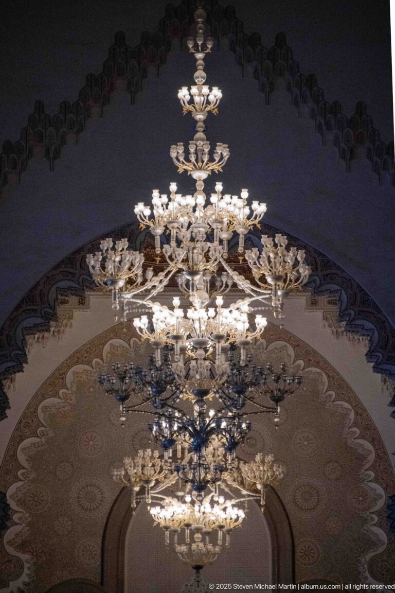 Large tiered chandelier suspended beneath a richly decorated arch inside the Hassan II Mosque.