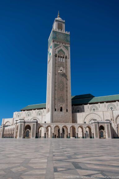 Closer view of the Hassan II Mosque minaret rising above the arcaded façade and open plaza.