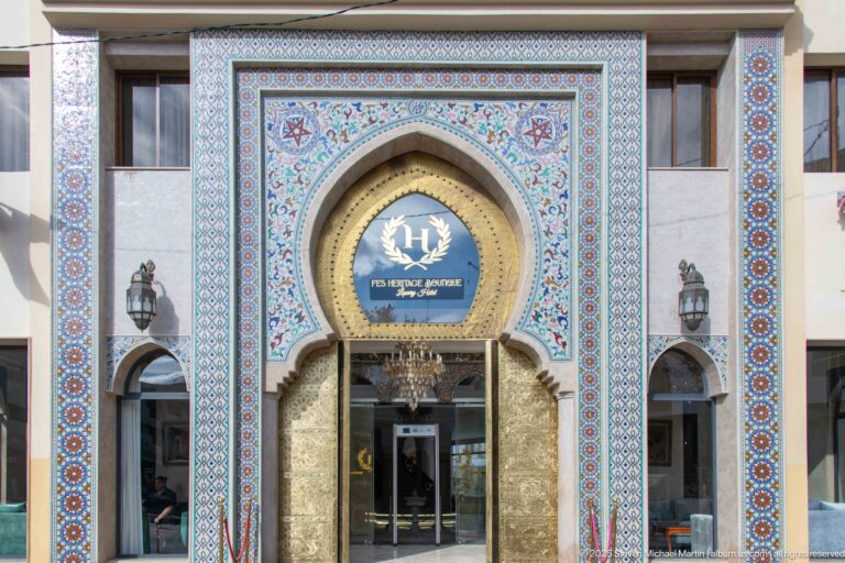 Entrance to Fes Heritage Boutique Hotel & Spa framed by multicolored geometric tilework and a large horseshoe arch.