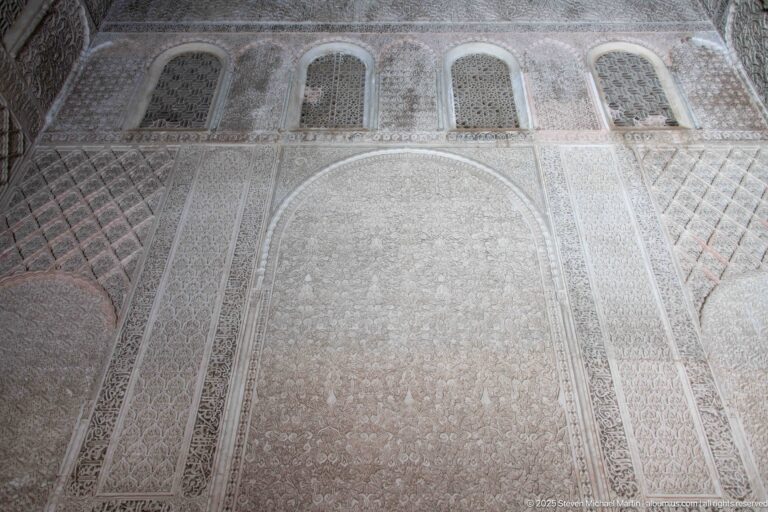 Large blind arch and three small upper openings surrounded by dense pale carved stucco ornament.