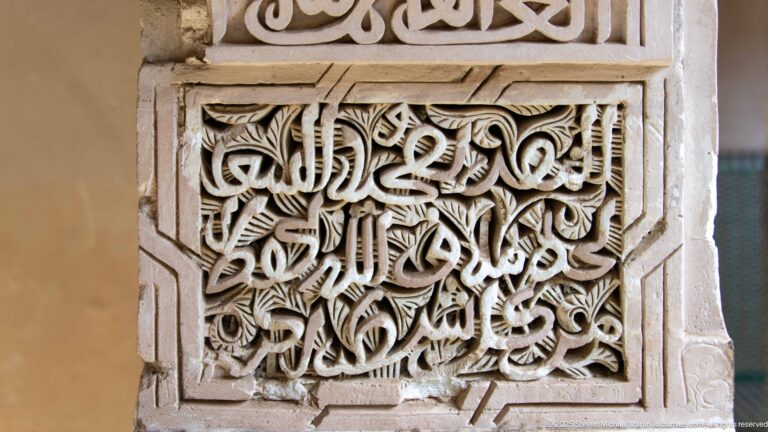 Square pierced plaster panel filled with interlaced Arabic calligraphy and vegetal carving in a geometric frame.