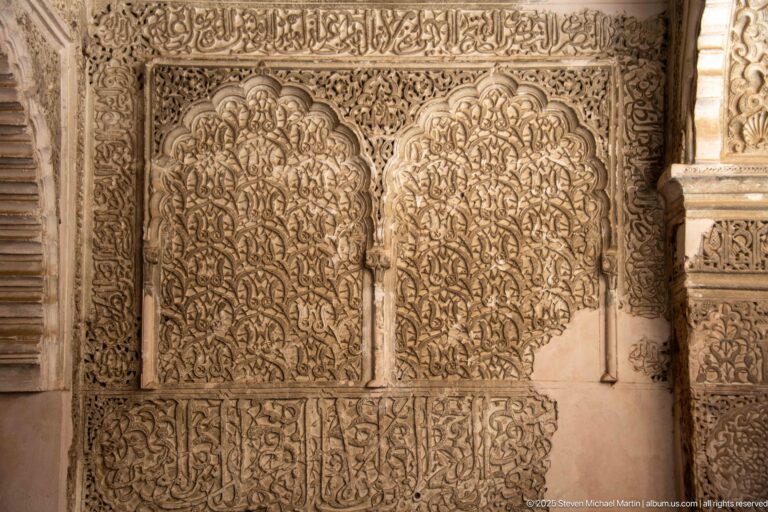 Two tall lobed carved stucco panels with dense vegetal ornament and decorative inscription bands above and below.