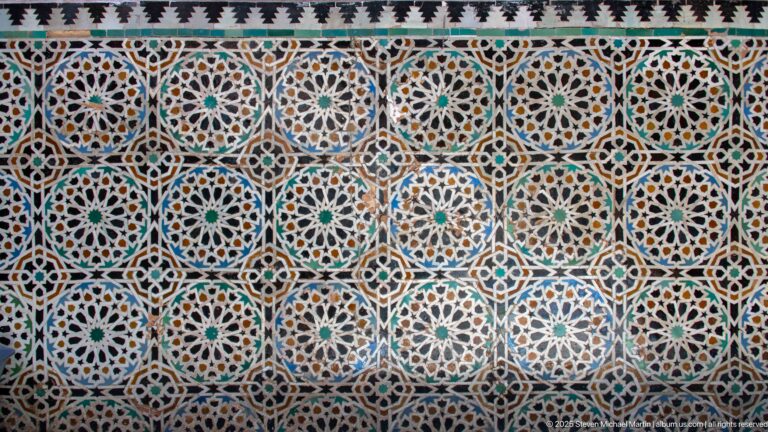 Close view of multicolored zellij mosaic made of repeating stars, rosettes, polygons, and interlocking geometric bands.