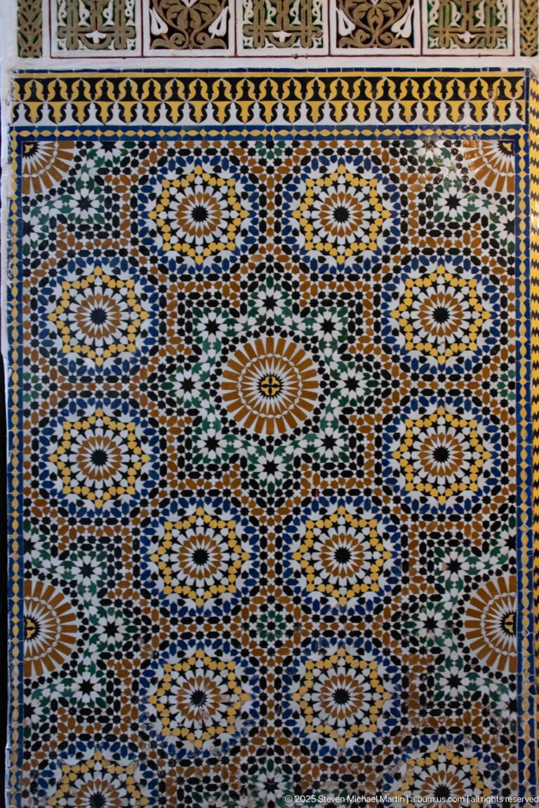 Close-up of multicolored zellij with large radial rosettes, star patterns, and geometric borders.