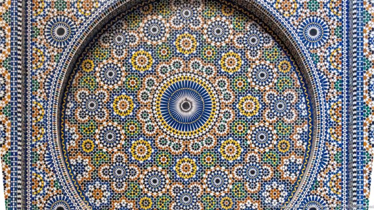 Large circular zellij rosette with concentric blue, green, yellow, white, and dark patterns surrounded by many smaller rosettes.