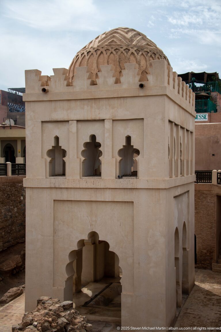 Frontal view of the Almoravid Qubba with lobed entrance, small upper openings, crenellated parapet, and ribbed dome.