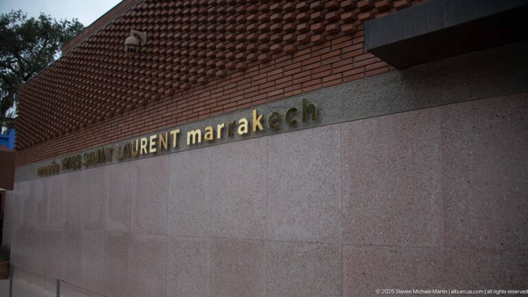 Gold Musée Yves Saint Laurent Marrakech lettering on a textured stone wall beneath a patterned brick façade.