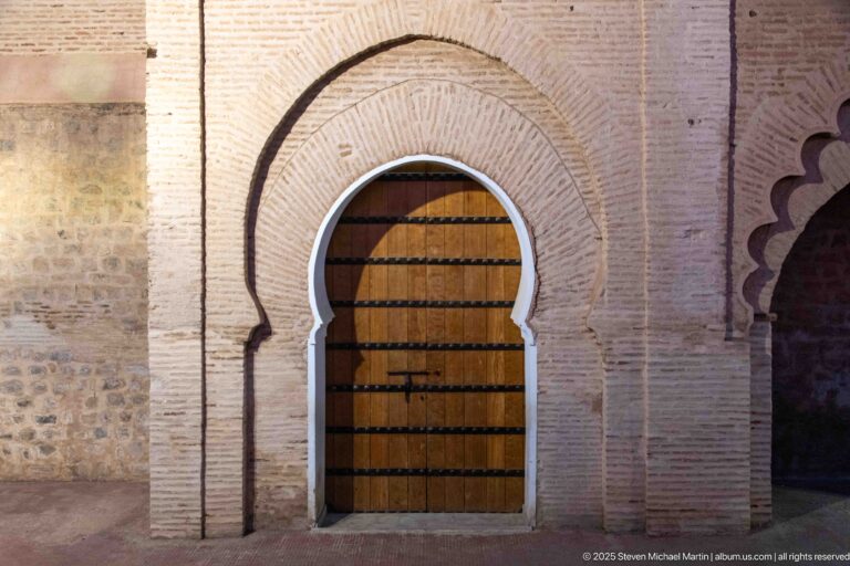 Wooden door set in a pointed horseshoe arch framed by layered brickwork at the Koutoubia Mosque precinct.