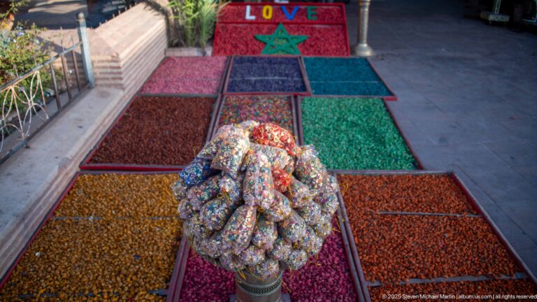 Rows of colorful spice and dried-goods bins with packaged goods piled at center and a red Moroccan-star “LOVE” display beyond.
